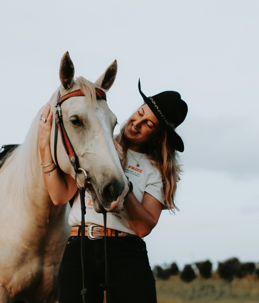 Brielle, founder of Northern Rivers Estate Services, smiling with her palomino horse in a paddock